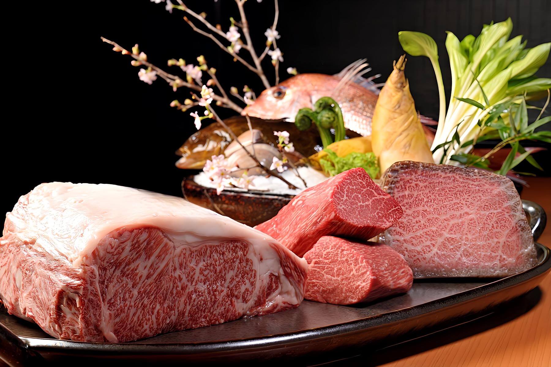 Selection of raw marbled Wagyu cuts with whole fish and seasonal vegetables
