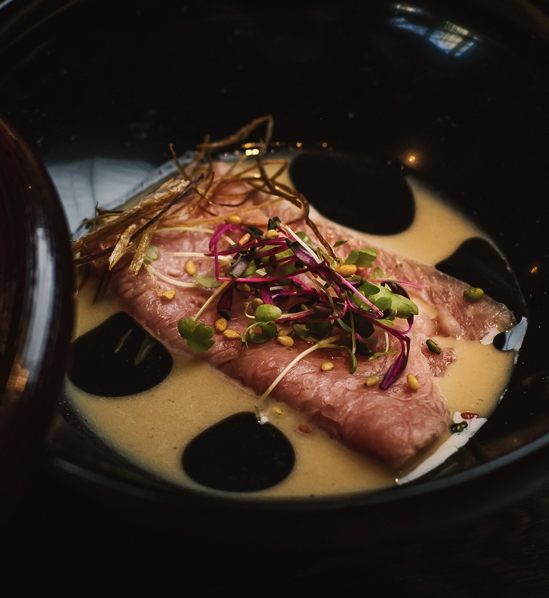 Thinly sliced Japanese Wagyu topped with microgreens and pine nuts at Togyushi