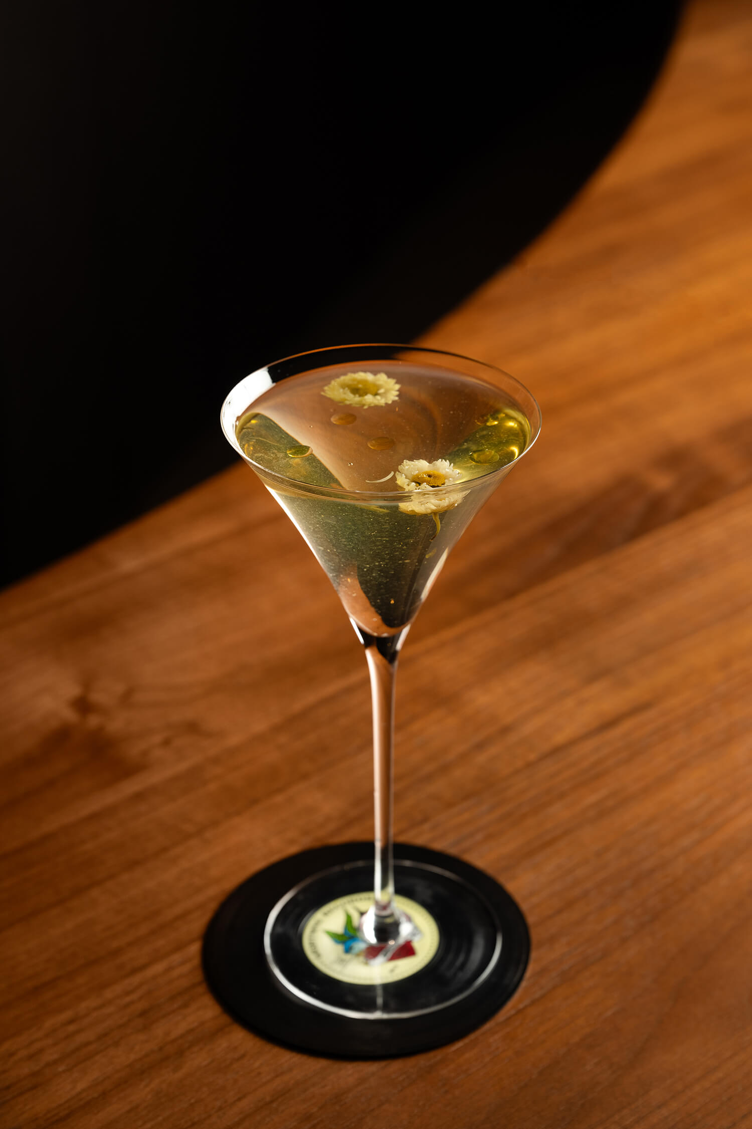 Clear cocktail with edible flower garnish on a vinyl record coaster