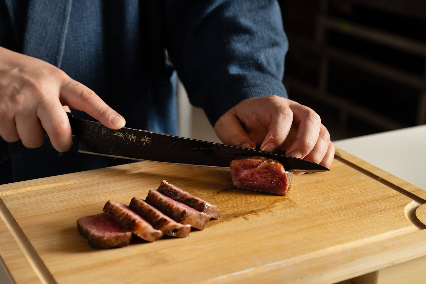Chef Ken Yamasaki slicing seared Wagyu on a cutting board