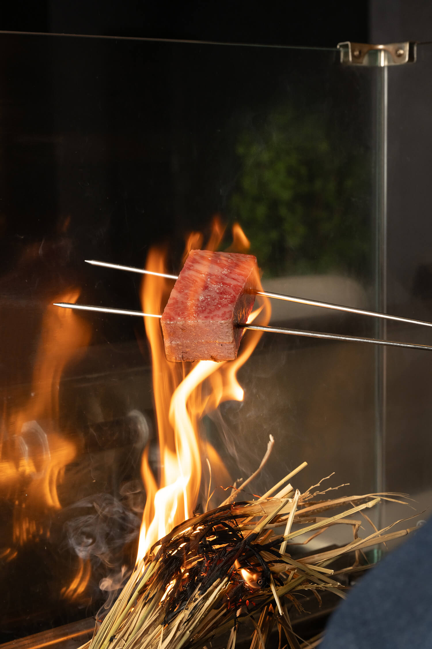 Rice-straw-infused Wagyu being seared over an open flame at Togyushi